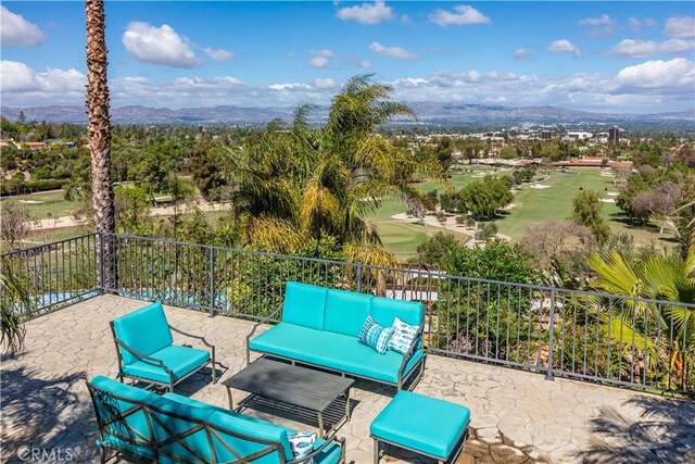 view of patio with a mountain view, view of golf course, fence, and an outdoor living space