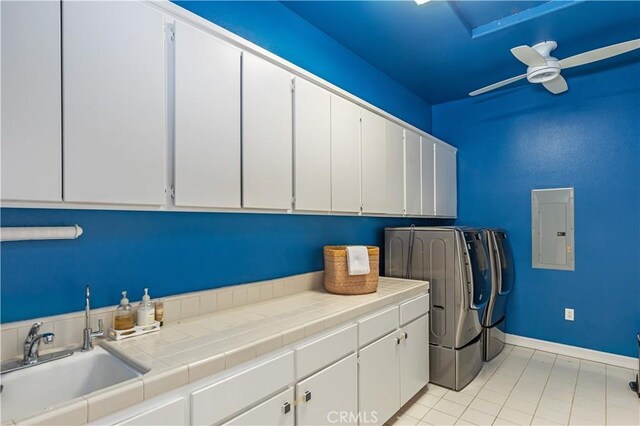 laundry room with cabinet space, electric panel, baseboards, independent washer and dryer, and a sink