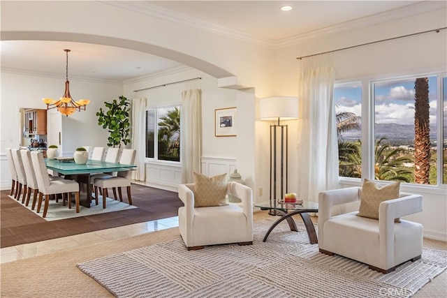 sitting room with arched walkways, a notable chandelier, a decorative wall, ornamental molding, and tile patterned flooring