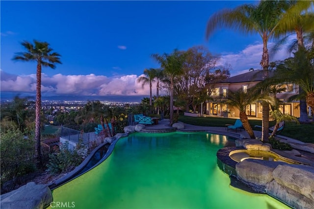 pool at dusk featuring fence, an outdoor pool, and a patio