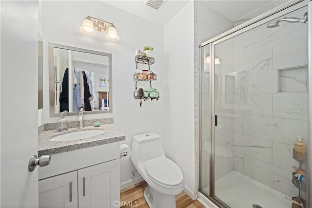 full bathroom with a stall shower, visible vents, toilet, wood finished floors, and vanity