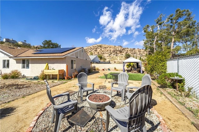 view of patio featuring a fenced backyard, a fire pit, a mountain view, and a gazebo