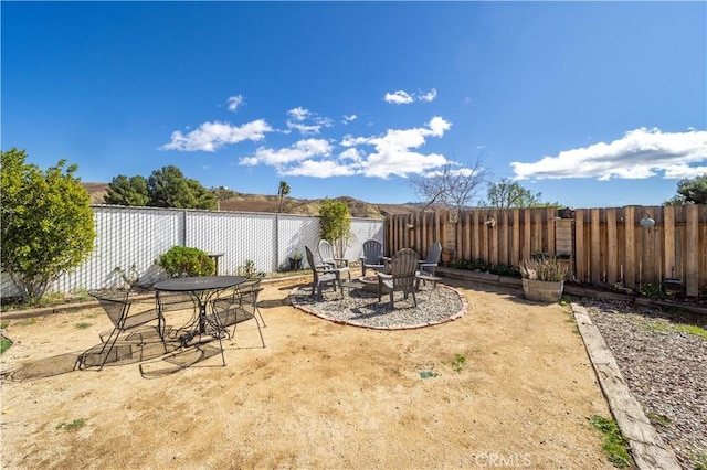 view of patio with a fenced backyard, a fire pit, and outdoor dining area