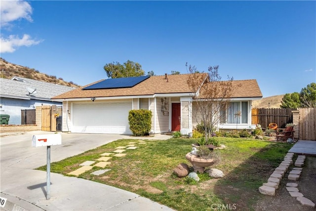 ranch-style home featuring concrete driveway, an attached garage, fence, and roof mounted solar panels