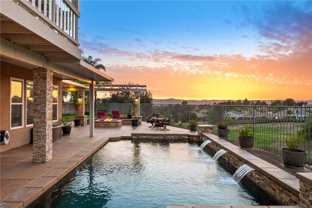 pool at dusk featuring a patio area, a fire pit, a fenced in pool, and a fenced backyard