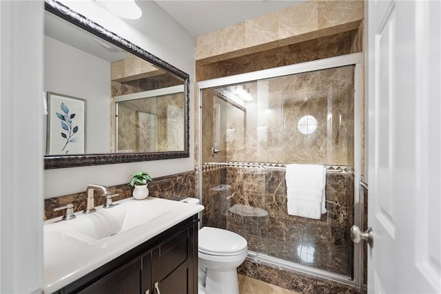 bathroom featuring vanity, tile walls, toilet, and a stall shower