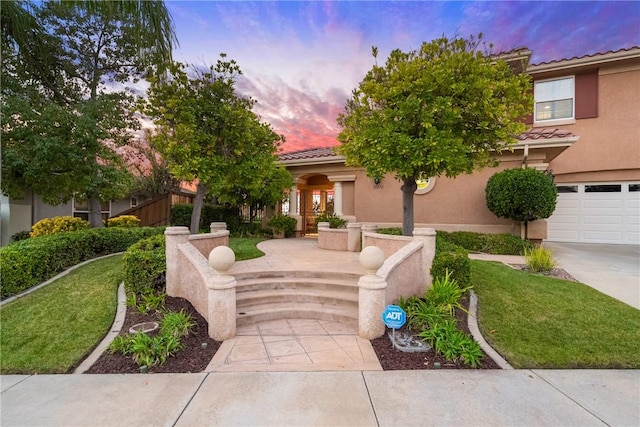 view of front of property with stucco siding, a yard, and a tiled roof