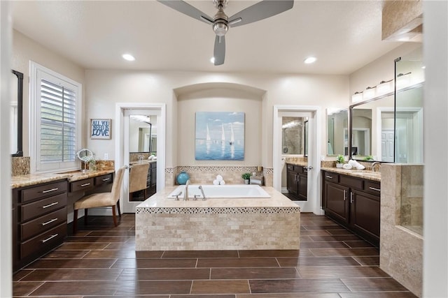 full bathroom with two vanities, a sink, ceiling fan, a bath, and wood tiled floor