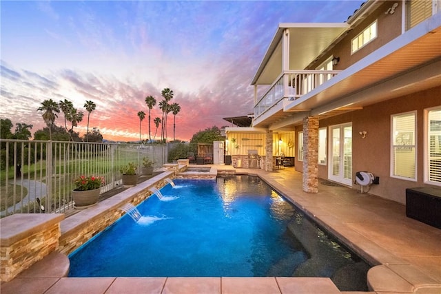 pool at dusk with a patio, a fenced backyard, french doors, a fenced in pool, and an outdoor kitchen