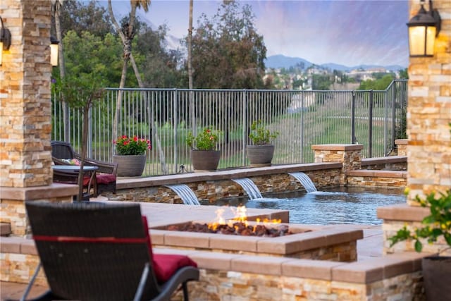 exterior space featuring a mountain view, a fire pit, and fence