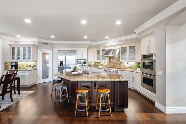 kitchen with under cabinet range hood, ornamental molding, stainless steel appliances, and dark wood-style flooring