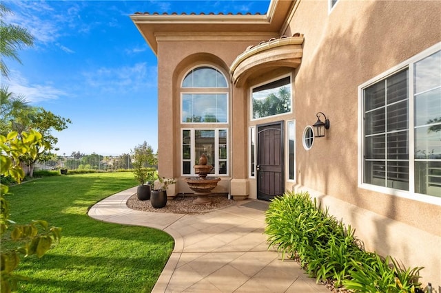 property entrance featuring stucco siding and a yard