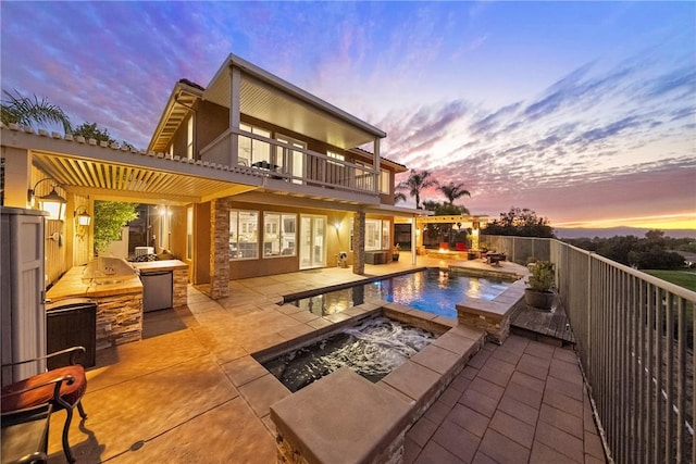 back of property at dusk featuring area for grilling, fence, a fenced in pool, a balcony, and a patio area