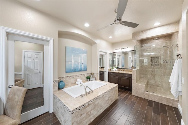 bathroom with a shower stall, wood finish floors, a bath, vanity, and a ceiling fan