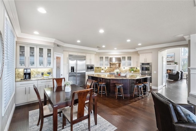 dining room featuring recessed lighting, a warm lit fireplace, dark wood-style floors, and crown molding