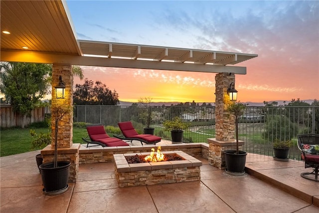 patio terrace at dusk with fence, a pergola, and a fire pit