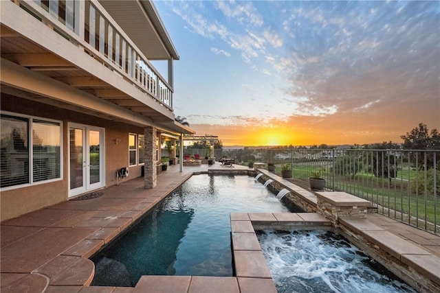 pool at dusk featuring a patio area, a fenced in pool, an in ground hot tub, and fence