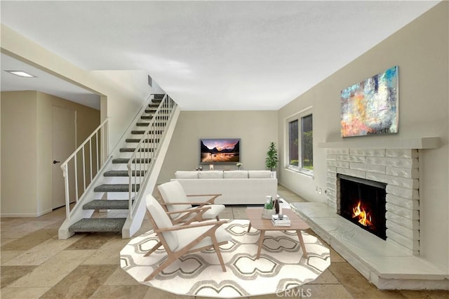 living area featuring stairs, stone finish flooring, and a fireplace