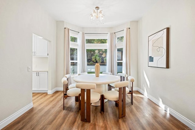 dining space featuring an inviting chandelier, baseboards, and wood finished floors