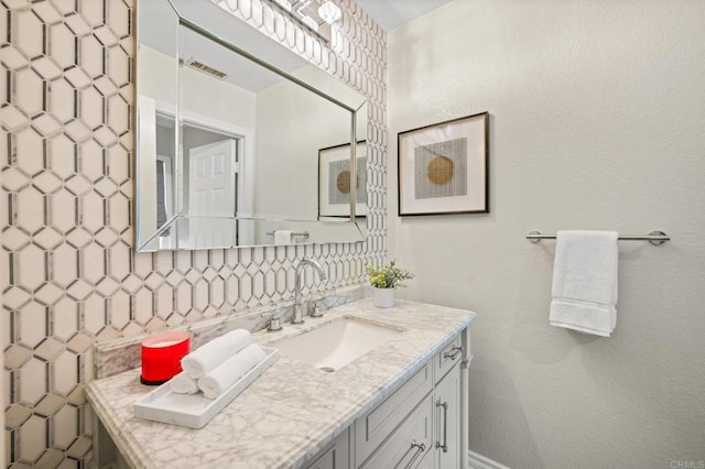 bathroom with tasteful backsplash, visible vents, a textured wall, and vanity