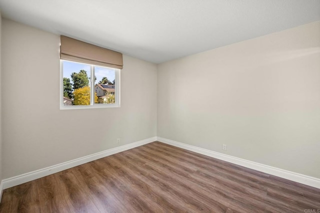 spare room featuring baseboards and wood finished floors