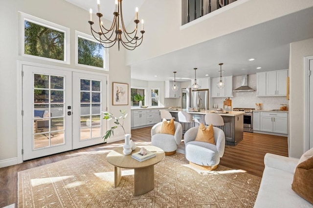 living area with a towering ceiling, baseboards, wood finished floors, and french doors