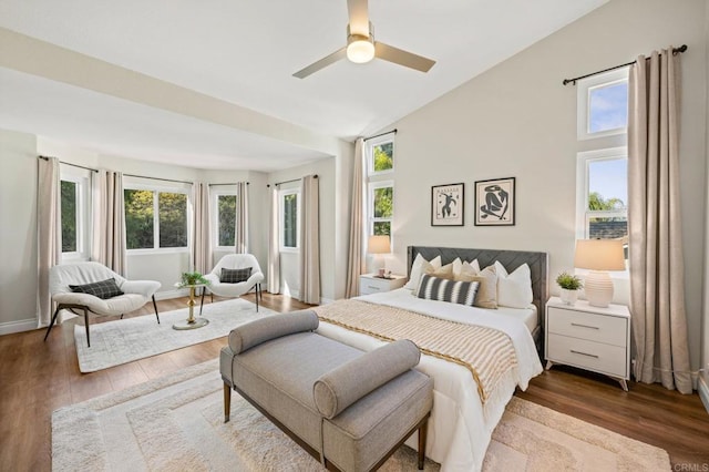 bedroom featuring lofted ceiling, multiple windows, baseboards, and wood finished floors