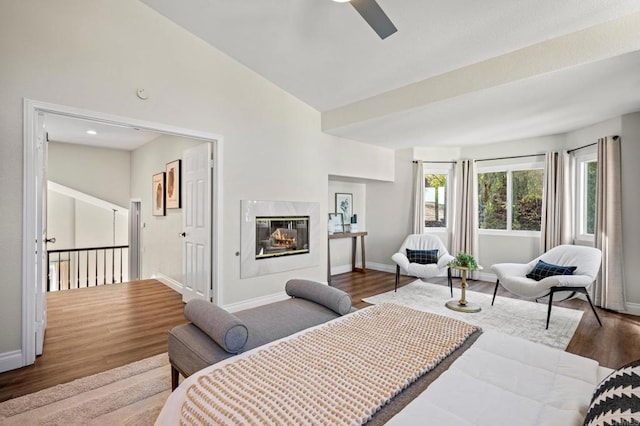 bedroom featuring lofted ceiling, a fireplace, baseboards, and wood finished floors