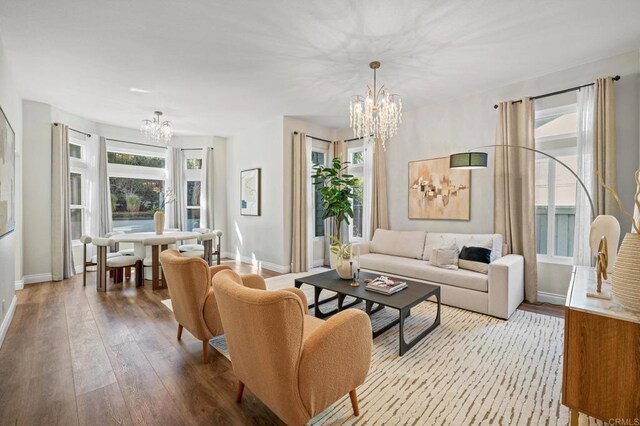 living area featuring baseboards, hardwood / wood-style floors, and an inviting chandelier