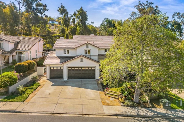 view of front of house with a tile roof, a chimney, concrete driveway, fence, and a garage