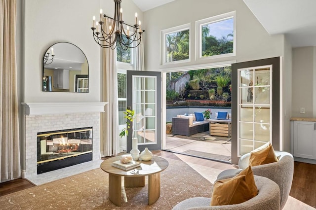 doorway to outside with a high ceiling, a chandelier, a fireplace, and wood finished floors