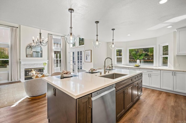 kitchen featuring light wood finished floors, light countertops, stainless steel dishwasher, and a sink