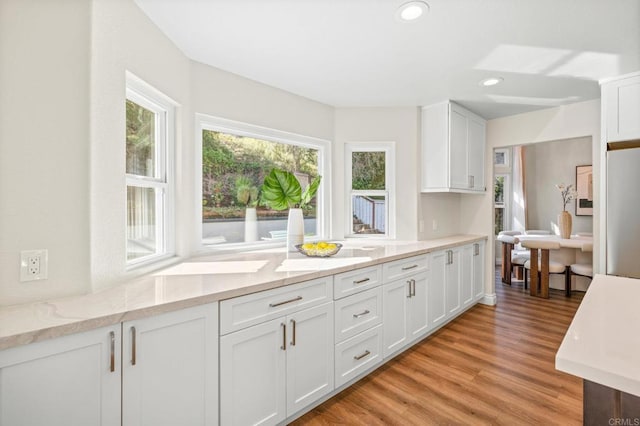 kitchen featuring refrigerator, recessed lighting, light wood-style flooring, white cabinets, and light stone countertops