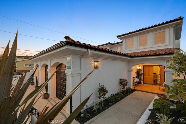 exterior space featuring a tile roof and stucco siding