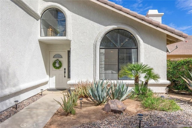 doorway to property featuring a tiled roof and stucco siding