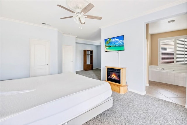 carpeted bedroom featuring crown molding, visible vents, a ceiling fan, a glass covered fireplace, and tile patterned floors