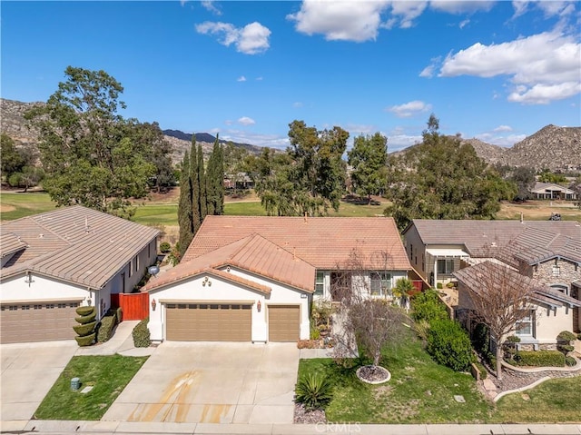 view of front of home featuring a garage, concrete driveway, a tiled roof, a mountain view, and stucco siding