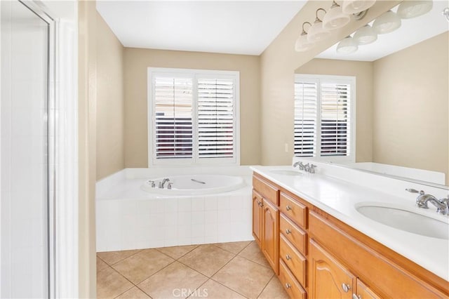 bathroom with double vanity, a garden tub, a sink, and tile patterned floors