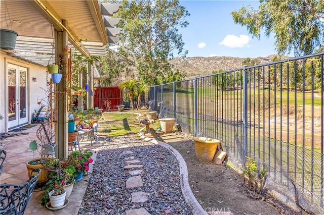 view of yard featuring a patio area, fence, a mountain view, and french doors