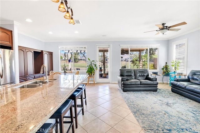 living room with light tile patterned floors, recessed lighting, visible vents, baseboards, and crown molding