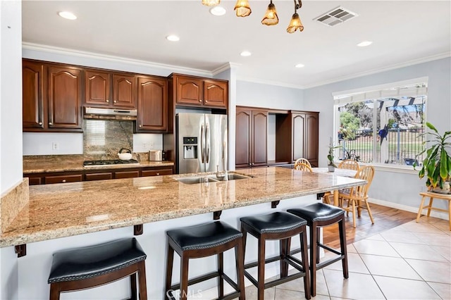 kitchen with visible vents, appliances with stainless steel finishes, ornamental molding, light stone countertops, and under cabinet range hood