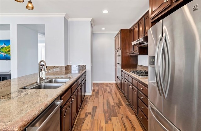 kitchen with stainless steel appliances, ornamental molding, a sink, light wood-type flooring, and under cabinet range hood