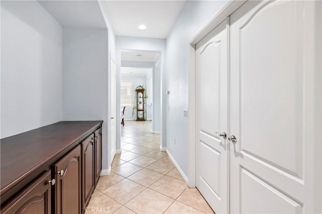 hall featuring light tile patterned floors and baseboards