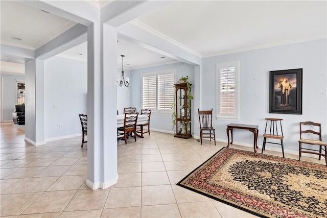 living area with light tile patterned flooring, crown molding, a notable chandelier, and baseboards