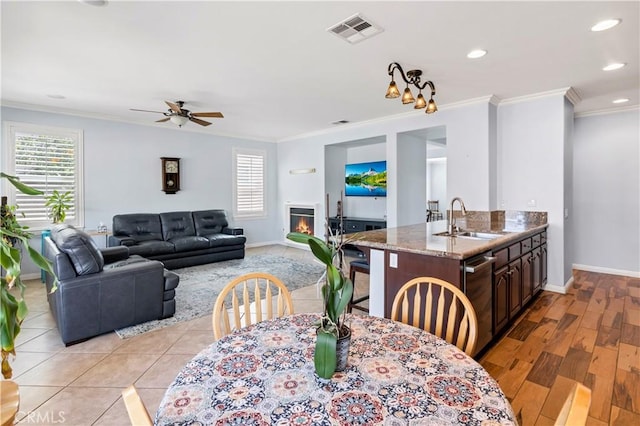 dining room featuring baseboards, a glass covered fireplace, visible vents, and crown molding