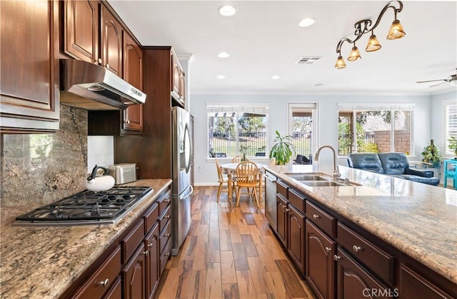 kitchen featuring visible vents, appliances with stainless steel finishes, ornamental molding, a sink, and under cabinet range hood