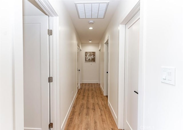 hallway with light wood-style floors, baseboards, visible vents, and recessed lighting