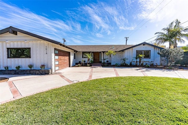 view of front facade with a garage, concrete driveway, board and batten siding, and a front lawn