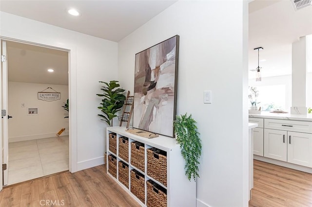 hallway with light wood-style flooring, recessed lighting, visible vents, and baseboards