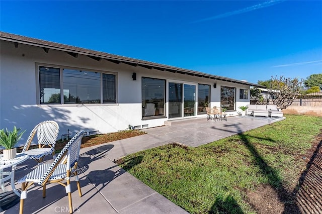 back of property featuring a patio, a lawn, fence, and stucco siding